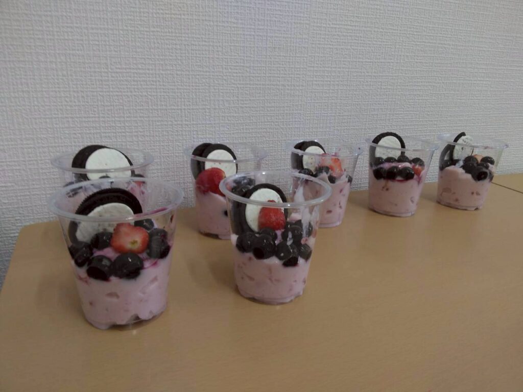 コップに入ったフルーチェにイチゴ、オレオに似たビスケット、ブルーベリーが乗っている。